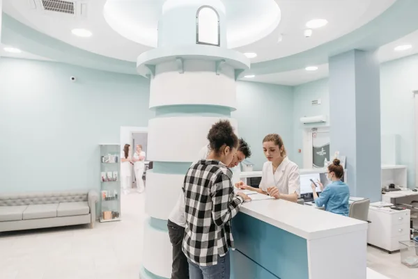 Casal sendo atendido por recepcionista no balcão de uma clínica clara e moderna