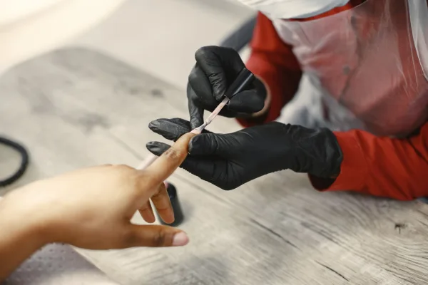 Manicure de luvas aplicando esmalte nas unhas de uma cliente em um salão
